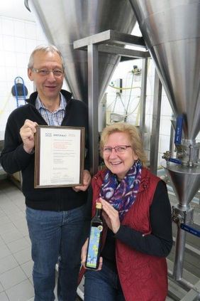 Marion Hoch und Wilfried Reiners vor der Sedimentationsanlage der Rapsölproduktion mit dem Zertifikat